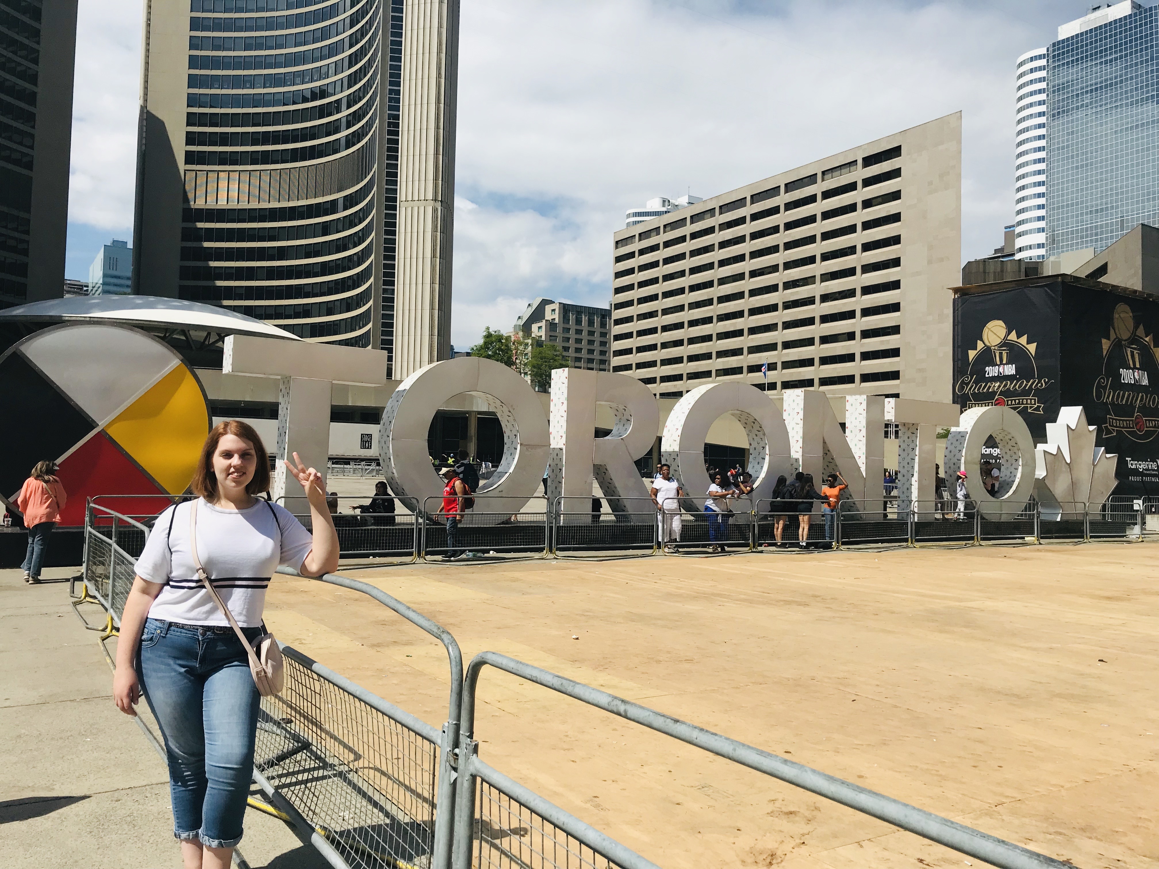 student stands in front of Toronto sign in Toronto, Ontario, Canada
