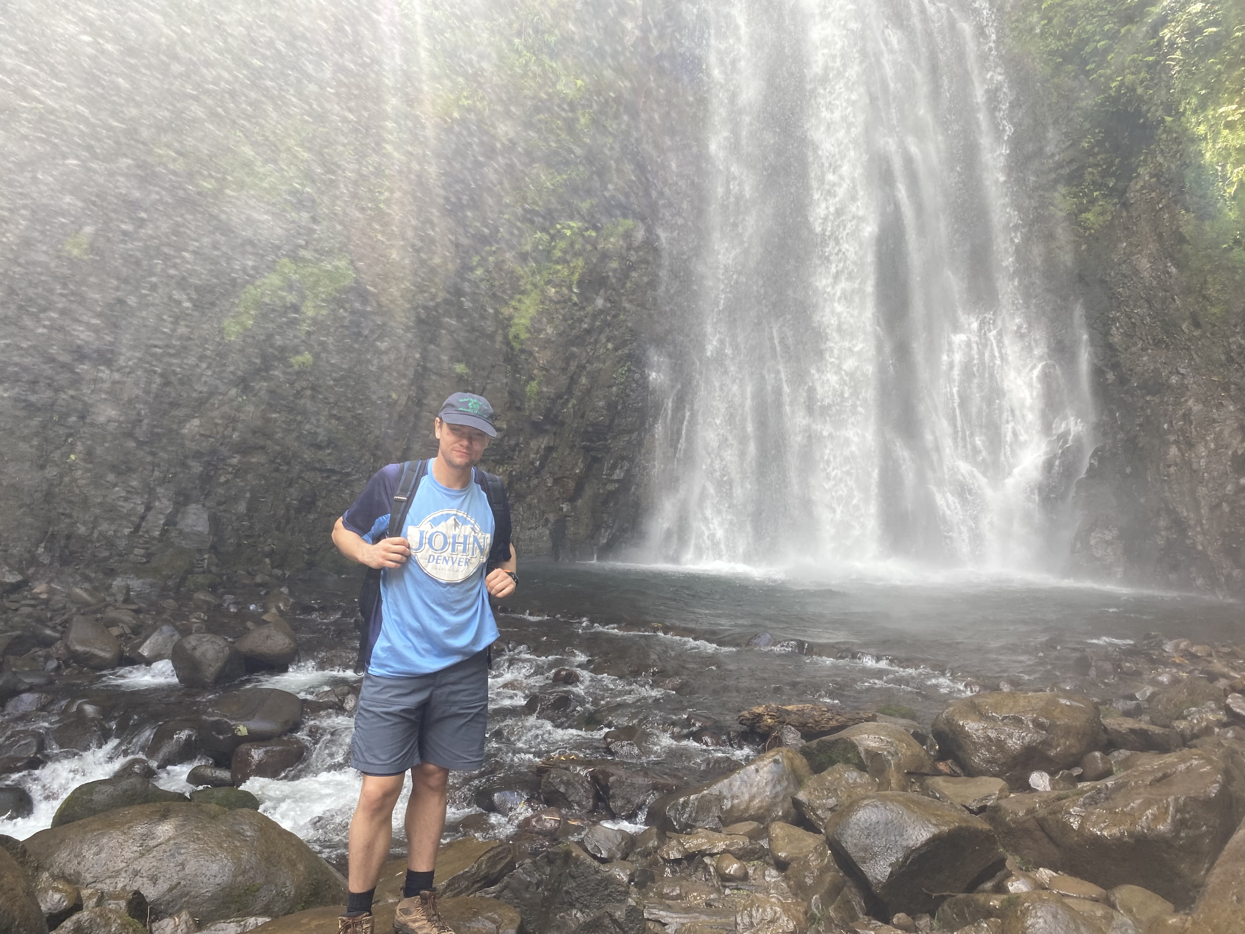 Image of student standing in front of a rainforest